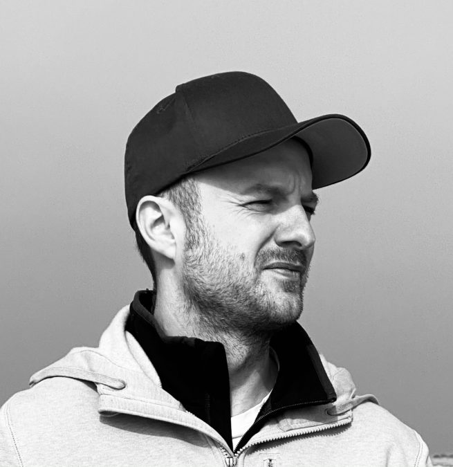 Black-and-white image of Nils where he is wearing a cap and looking to the right
